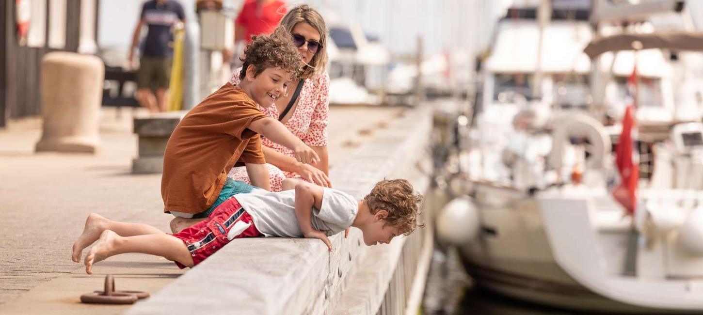 Tre mennesker som kigger ned på vandet i havnen