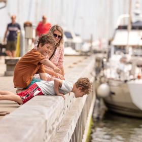 Tre mennesker som kigger ned på vandet i havnen