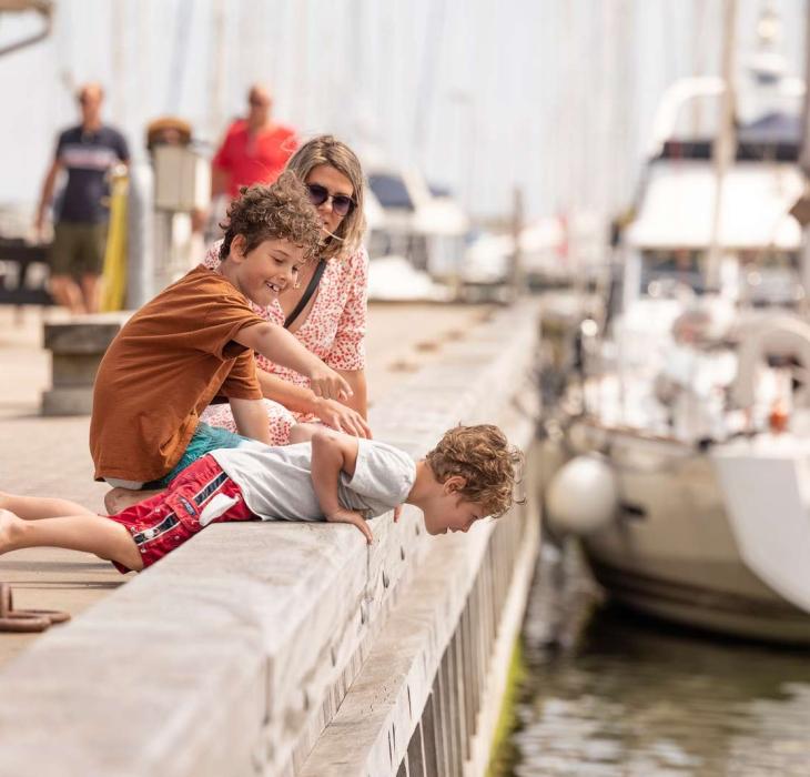 Tre mennesker som kigger ned på vandet i havnen